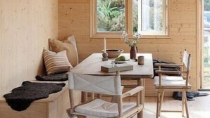 A wooden interior with a dining table, chairs, a bench, and a hanging light fixture. - Cottage gem with views of the Oslo Fjord (Akershus)