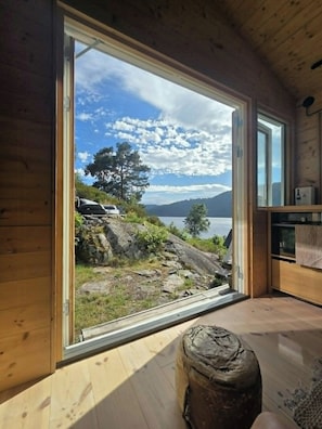 A wooden cabin with a large window offering a view of a lake and mountains. - Cottage gem with views of the Oslo Fjord (Akershus)