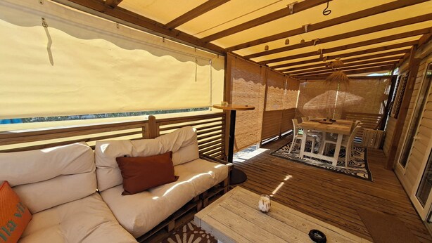 Un interior acogedor con un sofá, una mesa de centro de madera y una zona de comedor con una mesa y sillas.