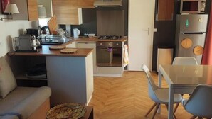 Un espacio habitable compacto con kitchenette, comedor y sofá.