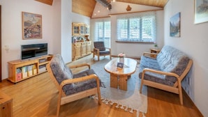 A cozy living room with wooden furniture, a television, and a bookshelf. - Haus Cervin - Inspiringplaces Zermatt (Zermatt)