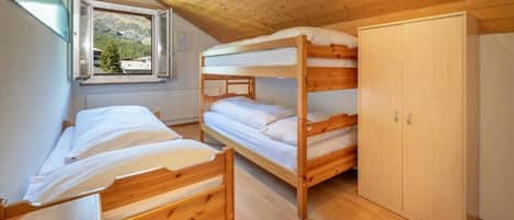 Una habitación con literas, un armario y una ventana con vista a árboles.