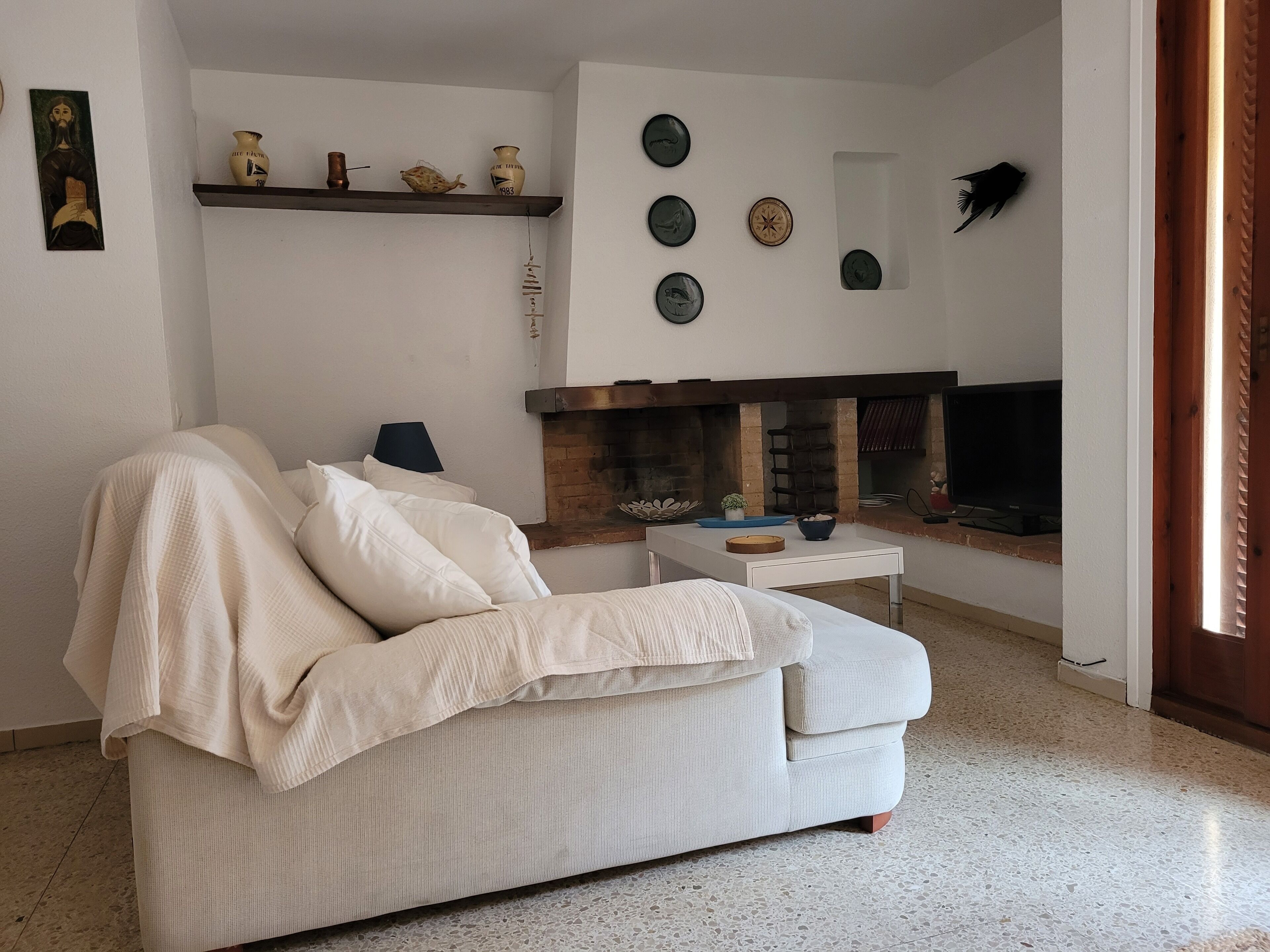 Uma sala de estar com sofá, lareira e pratos decorativos na parede.