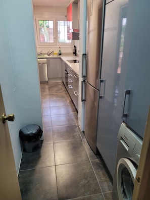 A compact kitchen with a dishwasher, a refrigerator, and a washing machine. - Beach Apt: Huge 80m² Private Terrace, 2 Min Walk to Beach &  Free Parking (Tamariu)