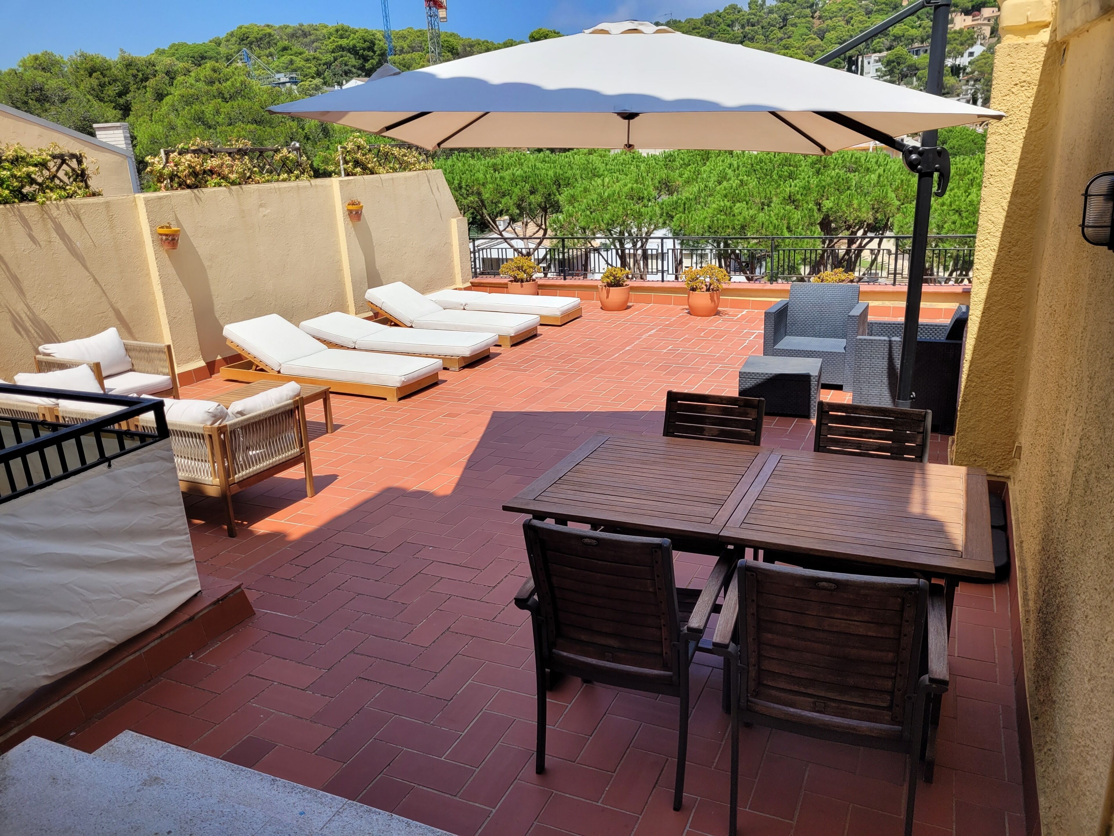 An outdoor patio with lounge chairs, a table, and umbrellas.