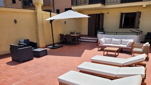 A sunlit outdoor seating area with lounge chairs, a table, and a sofa.