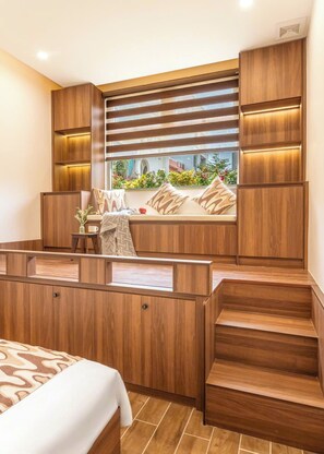 A modern bedroom with a built-in window seat, wooden furniture, and a view of greenery outside. - Private vacation house in An Thuong - beach-near (Đà Nẵng)