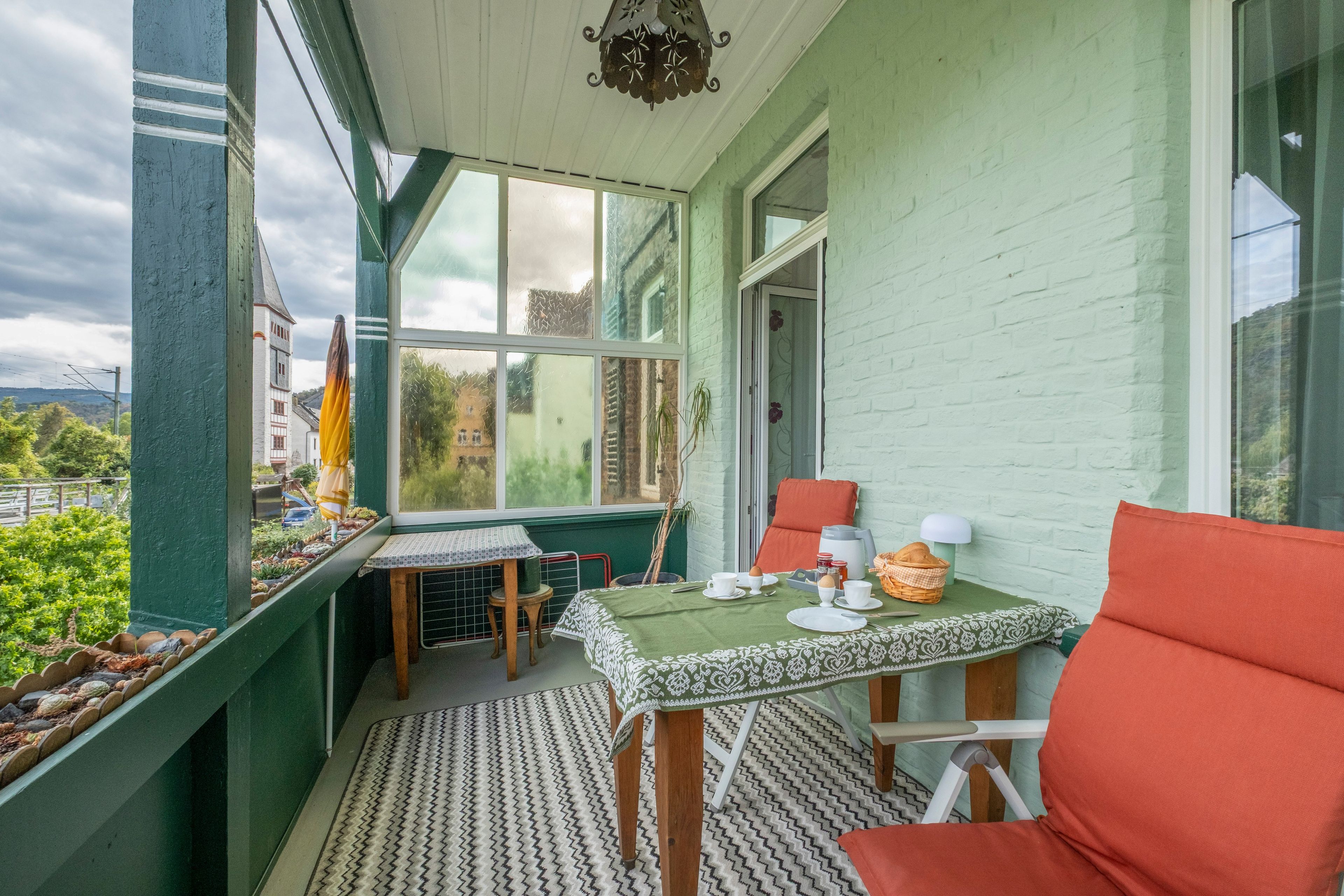 A cozy room with a table set for breakfast, a chair, and a view of greenery outside.