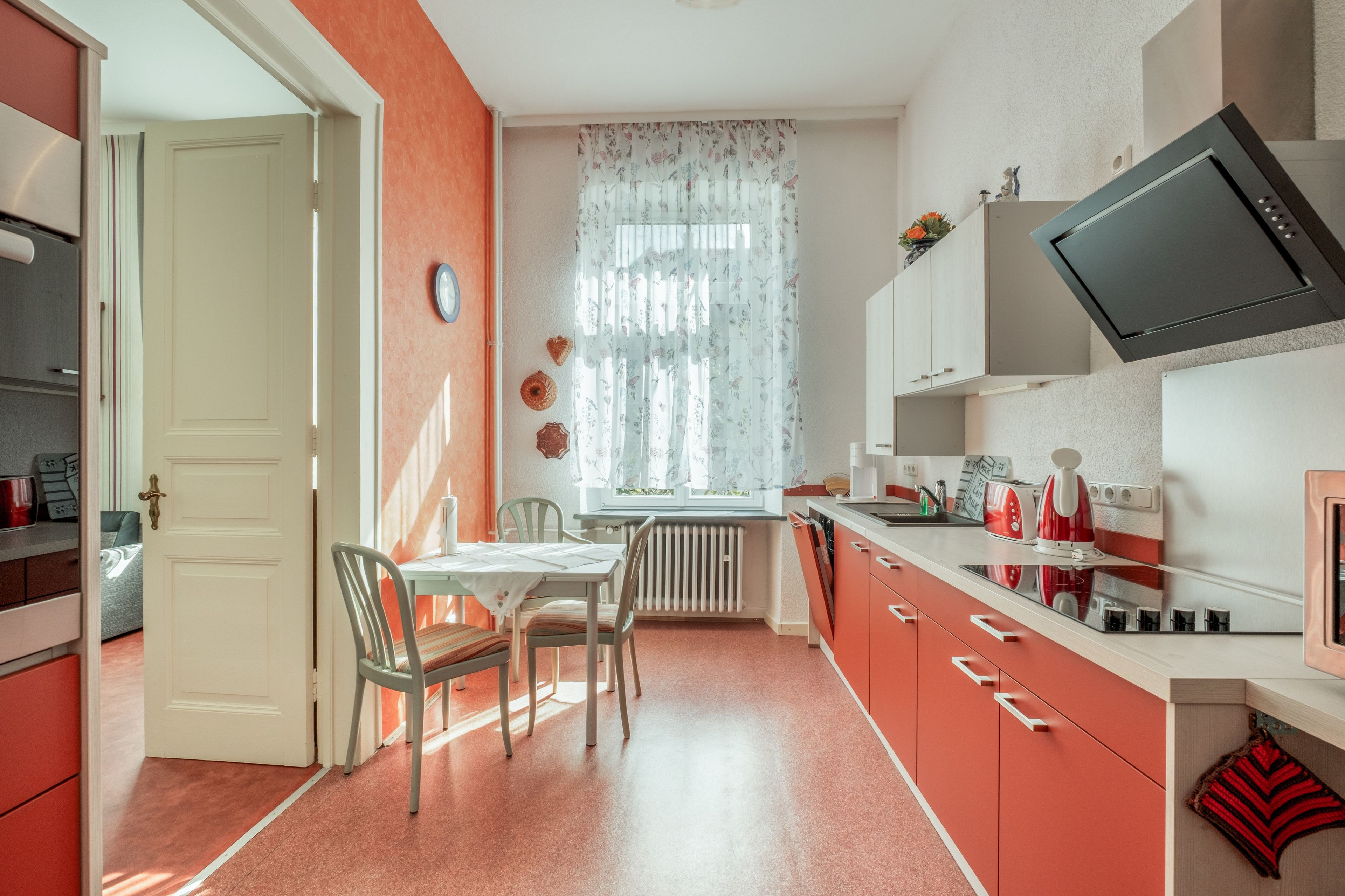 Ett kompakt kök med en matplats, utrustat med en element, en tv och ett fönster med blommiga gardiner.