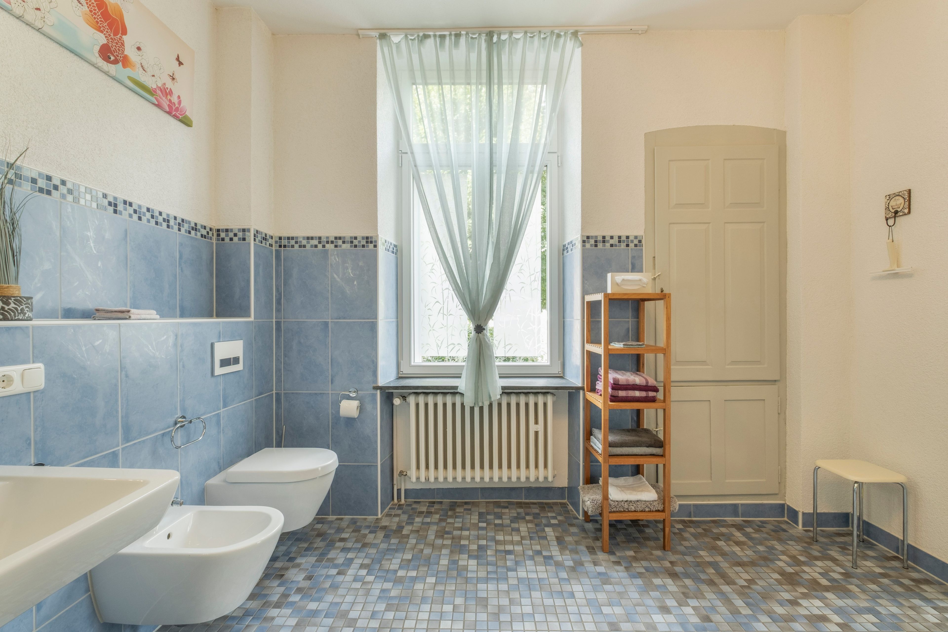 Un baño con inodoro, bidé y un estante con toallas.