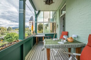 A balcony with a table set for breakfast, a view of a distant building, and a green railing.