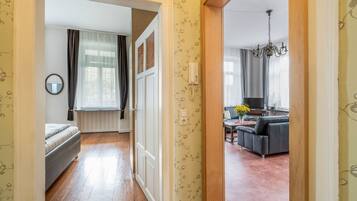 En hall som leder in till ett vardagsrum med en soffa, en tv och en kristallkrona.