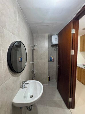 Een badkamer met een wastafel, spiegel, douche en toilet.