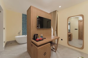 Ein modernes Badezimmer mit einer freistehenden Badewanne, einem Holzwaschtisch mit Spiegel und einem an der Wand montierten Fernseher.