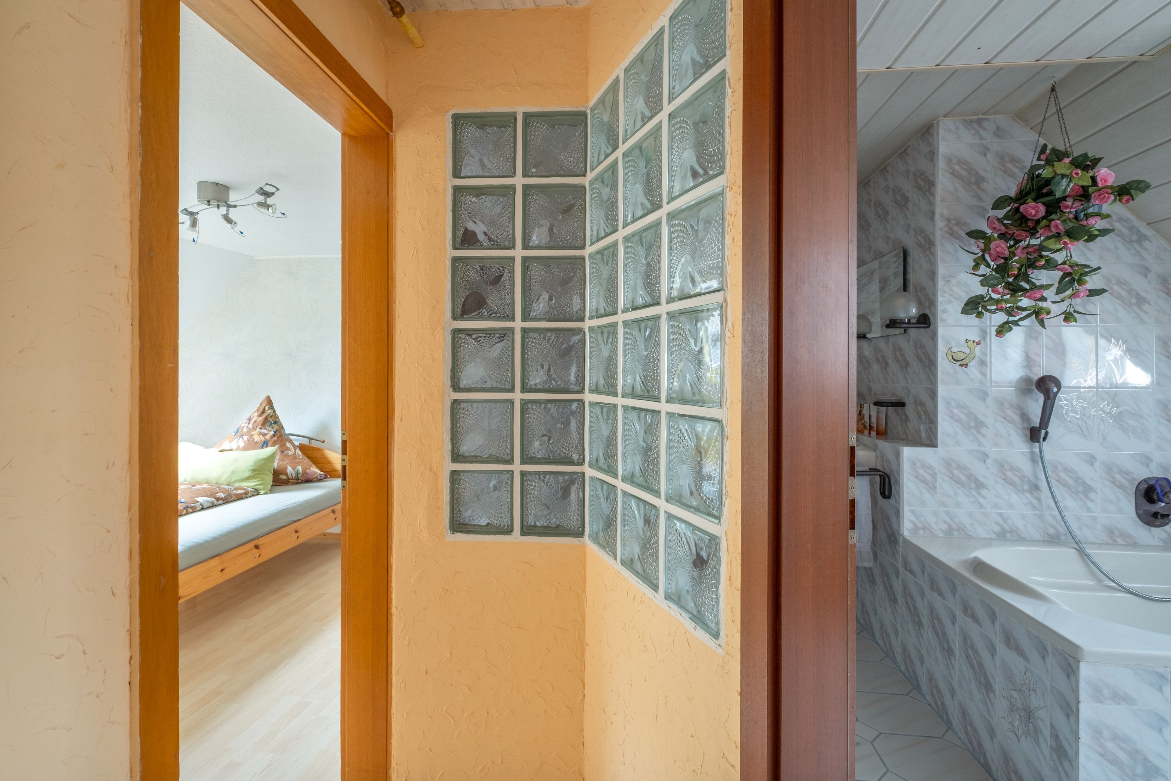 Un baño con ducha, inodoro y lavamanos. Cuenta con un ventanal con paneles de vidrio decorativo.