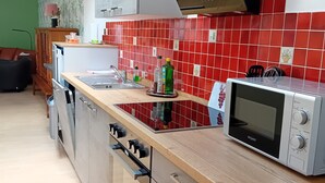 A modern kitchen with a microwave, stove, and red-tiled backsplash.