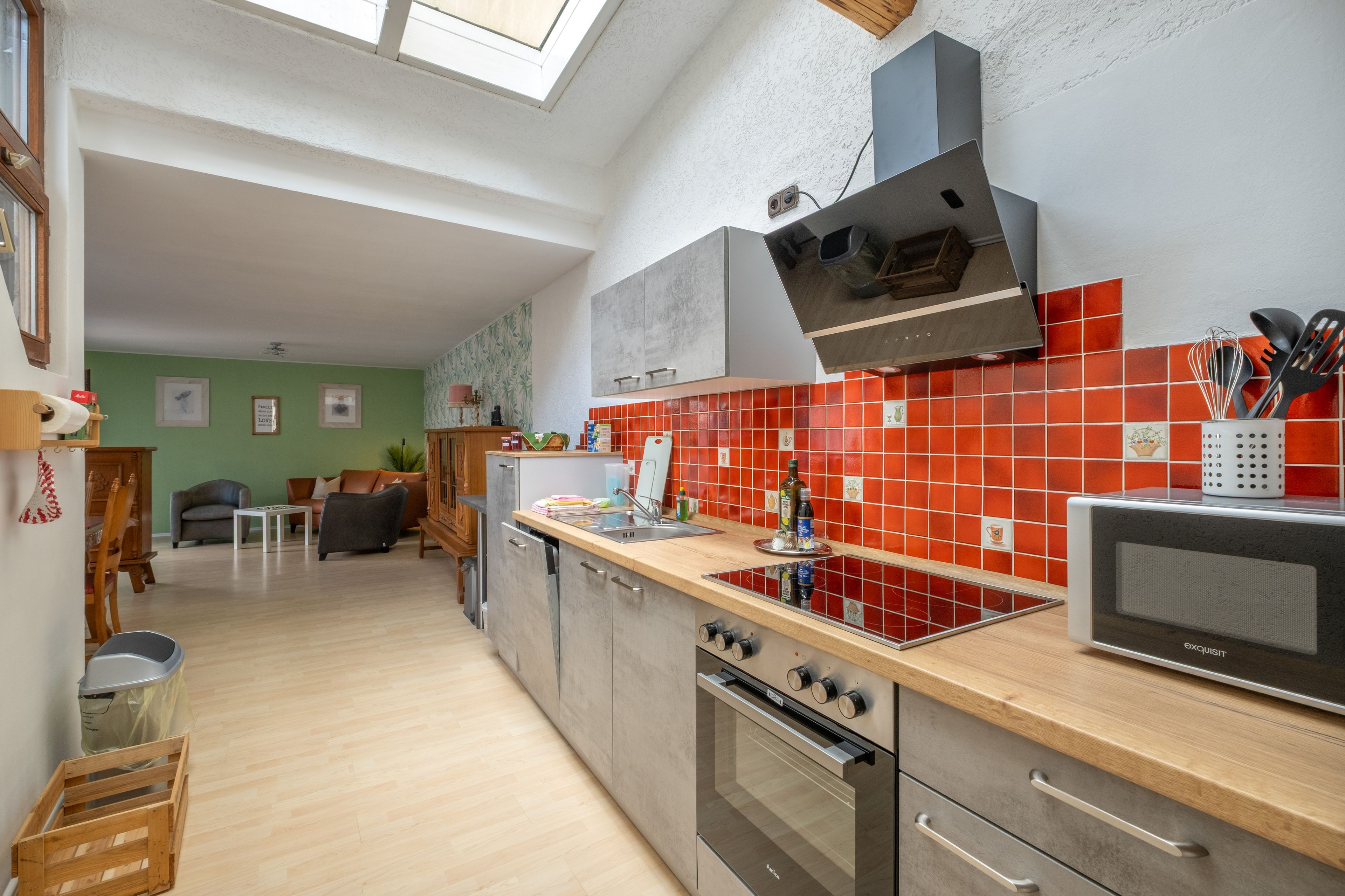 Una cucina moderna con forno a incasso, microonde e rivestimento a mosaico rosso.