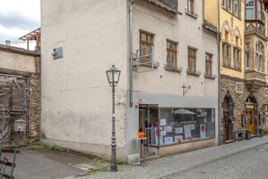 Une vue de rue avec un immeuble abritant un magasin dont la façade est en verre, un lampadaire en métal et un trottoir pavé.