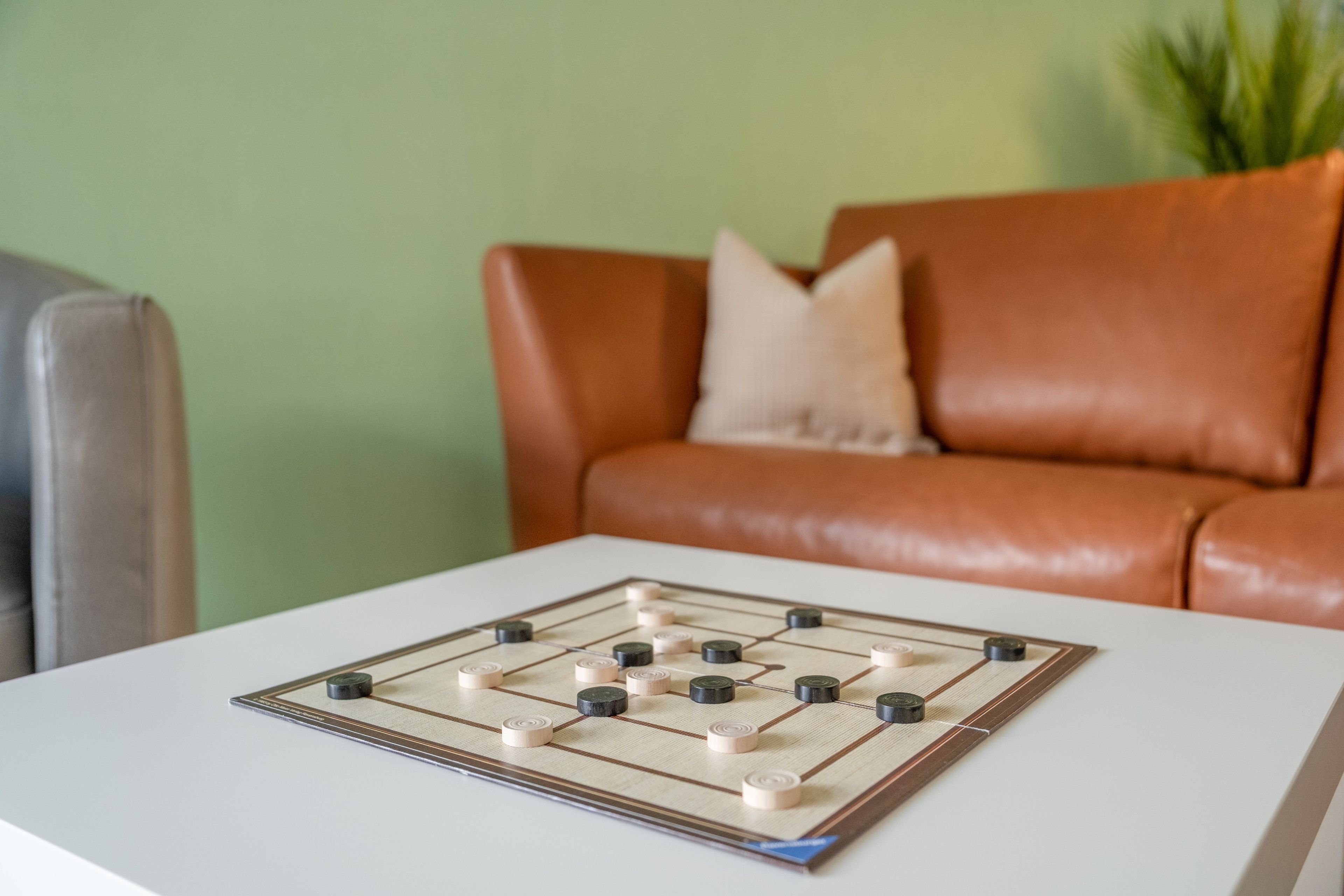 Un juego de mesa sobre una mesa blanca, con un sofá y un cojín al fondo.