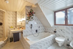 Une salle de bain avec une baignoire, des toilettes, un lavabo et une fenêtre.