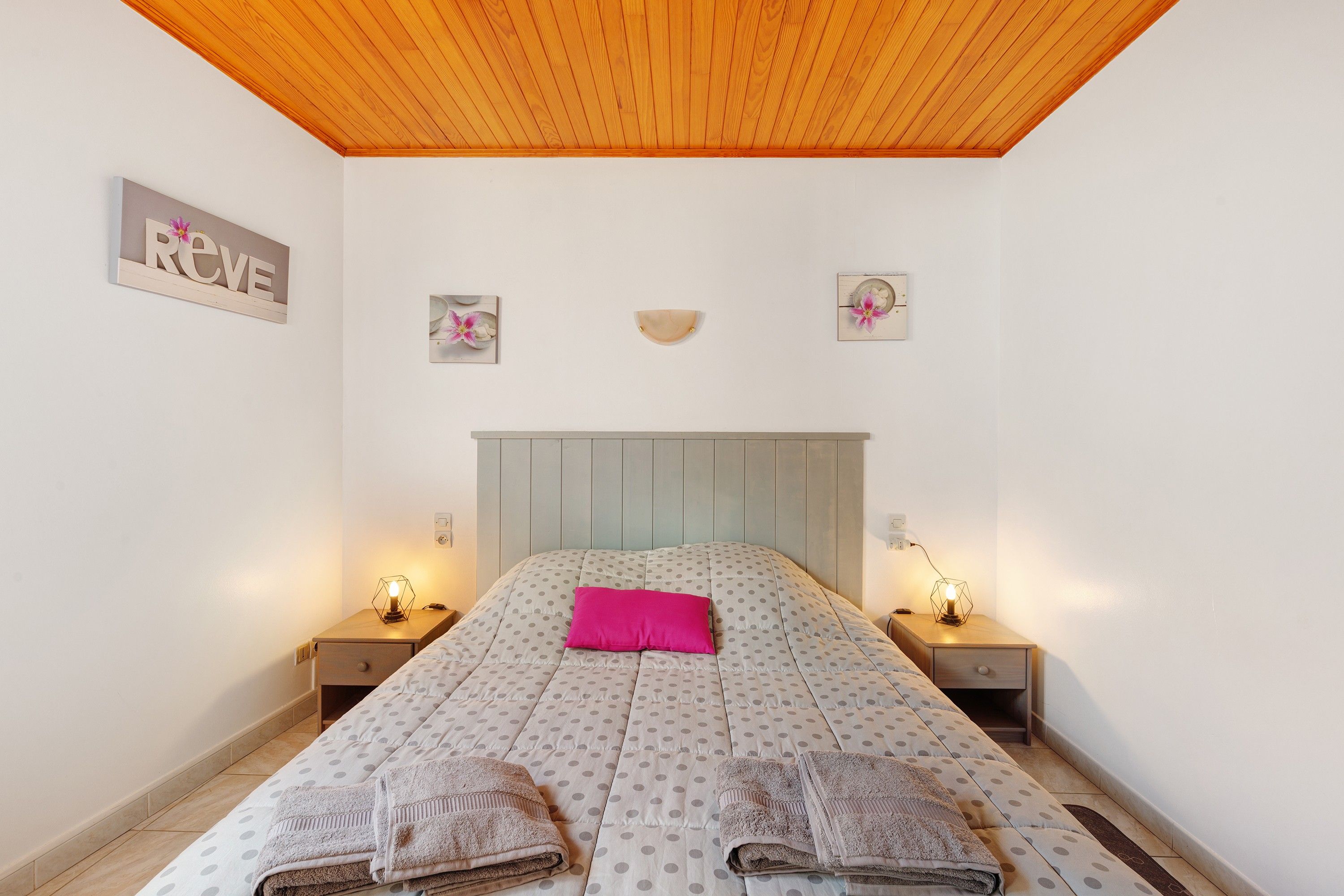 Quarto com cama, duas mesas de cabeceira, encosto de cama e decoração na parede.