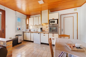 A compact kitchen with white cabinets, a microwave, an oven, and a sink.