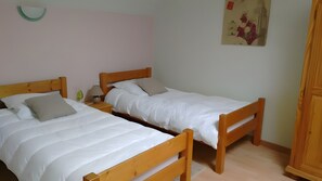 Two wooden beds with white bedding, a nightstand with a lamp, and a wall-mounted light fixture. - Holiday Home “Gîte du Soleil Levant” with Private Garden and Wi-Fi (Saint-Valery-sur-Somme)