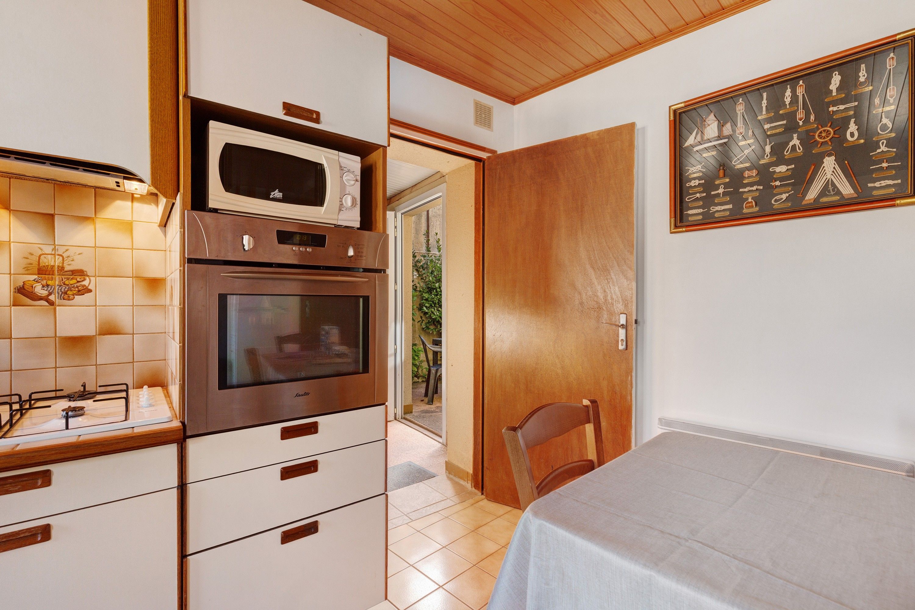 A kitchen with a built-in oven and microwave, a dining area with a table and chairs, and a door leading to an outdoor space.