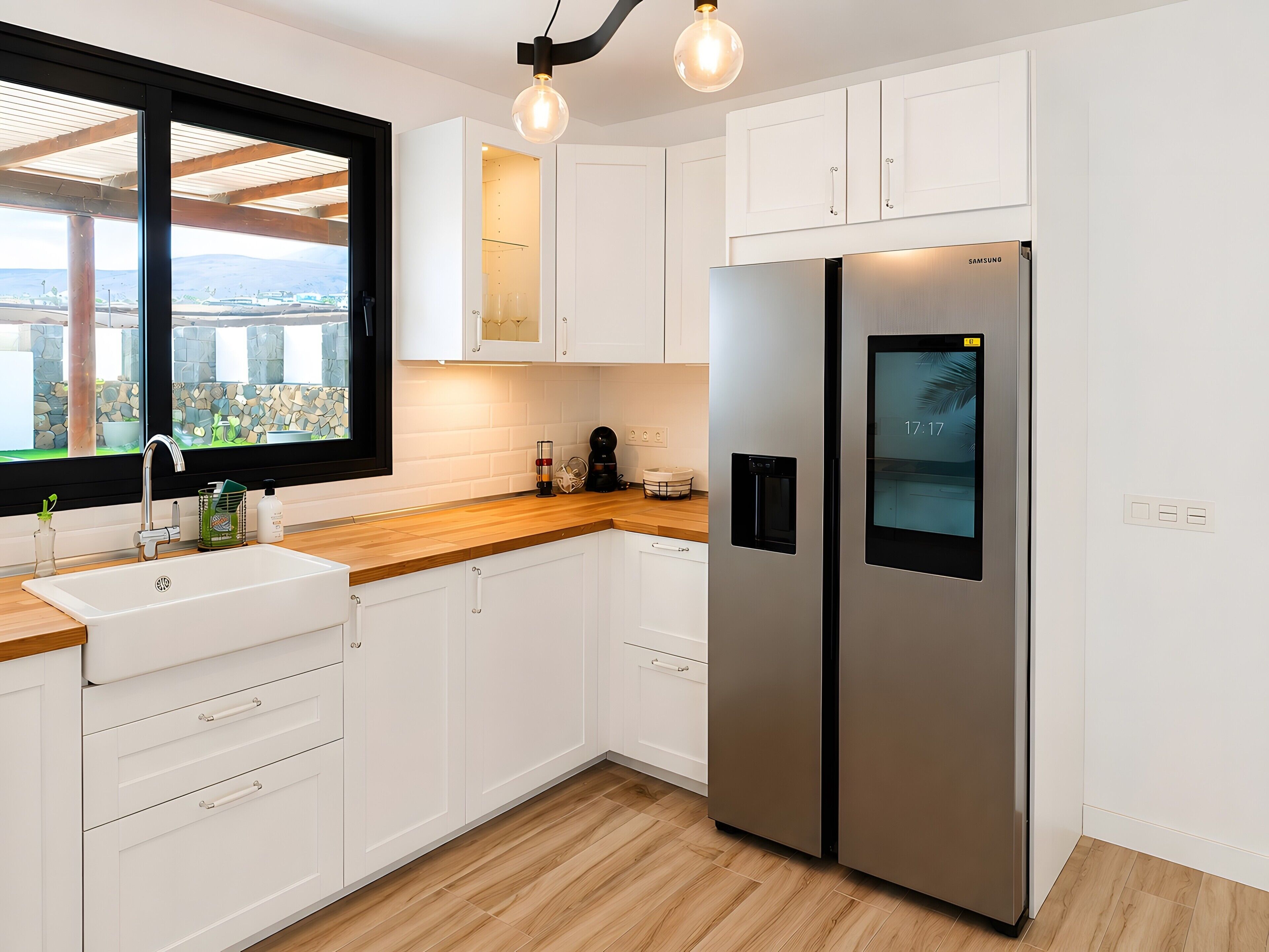 A modern kitchen with white cabinets, a stainless steel refrigerator, a wooden countertop, and a window with a view of the city.