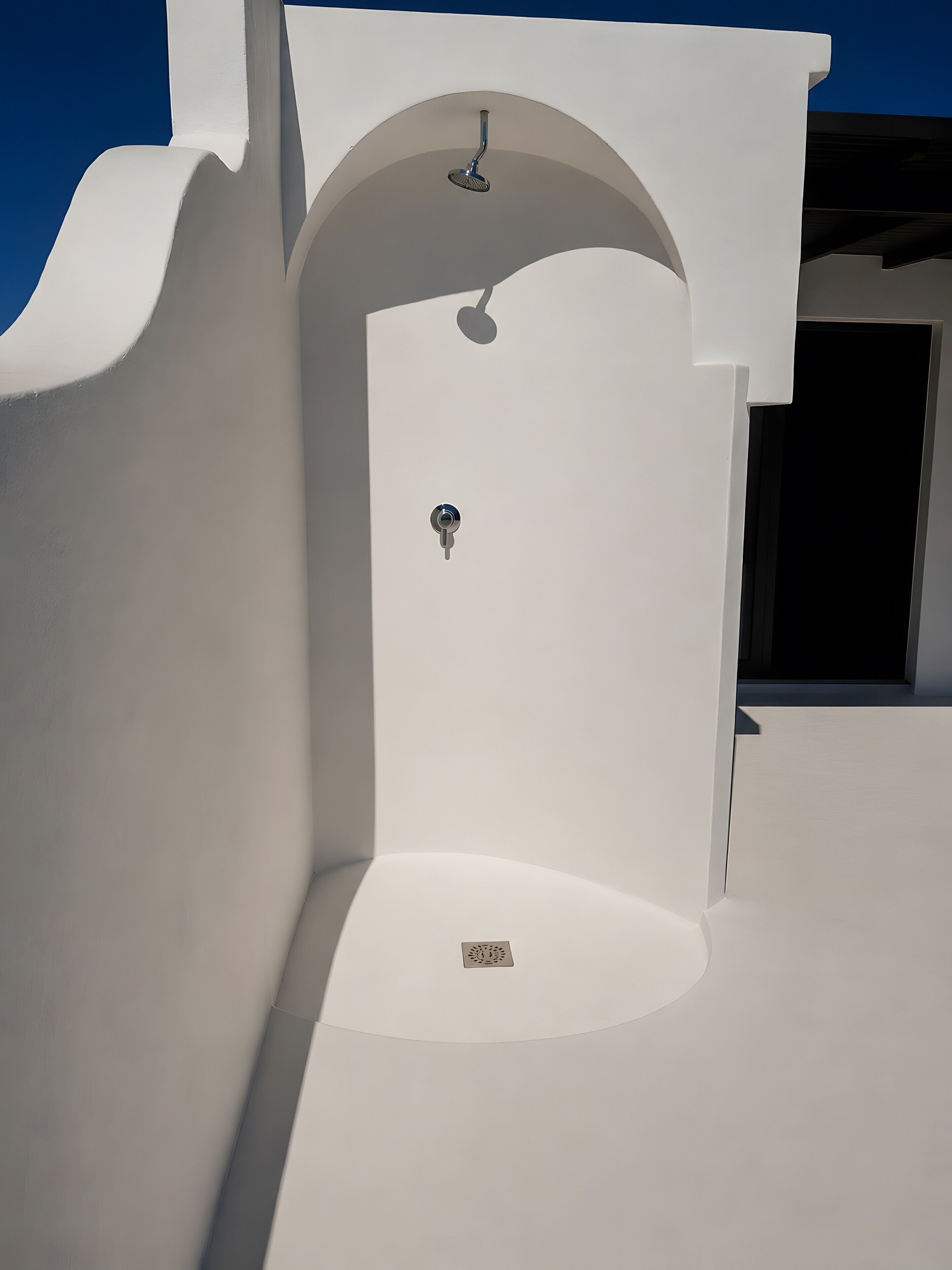 Una estructura arquitectónica blanca con una puerta y un cabezal de ducha.