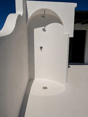 Edifici blanc amb una porta i un braç de dutxa.
