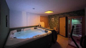 A room with a hot tub, a wooden door, and a staircase leading to another level.