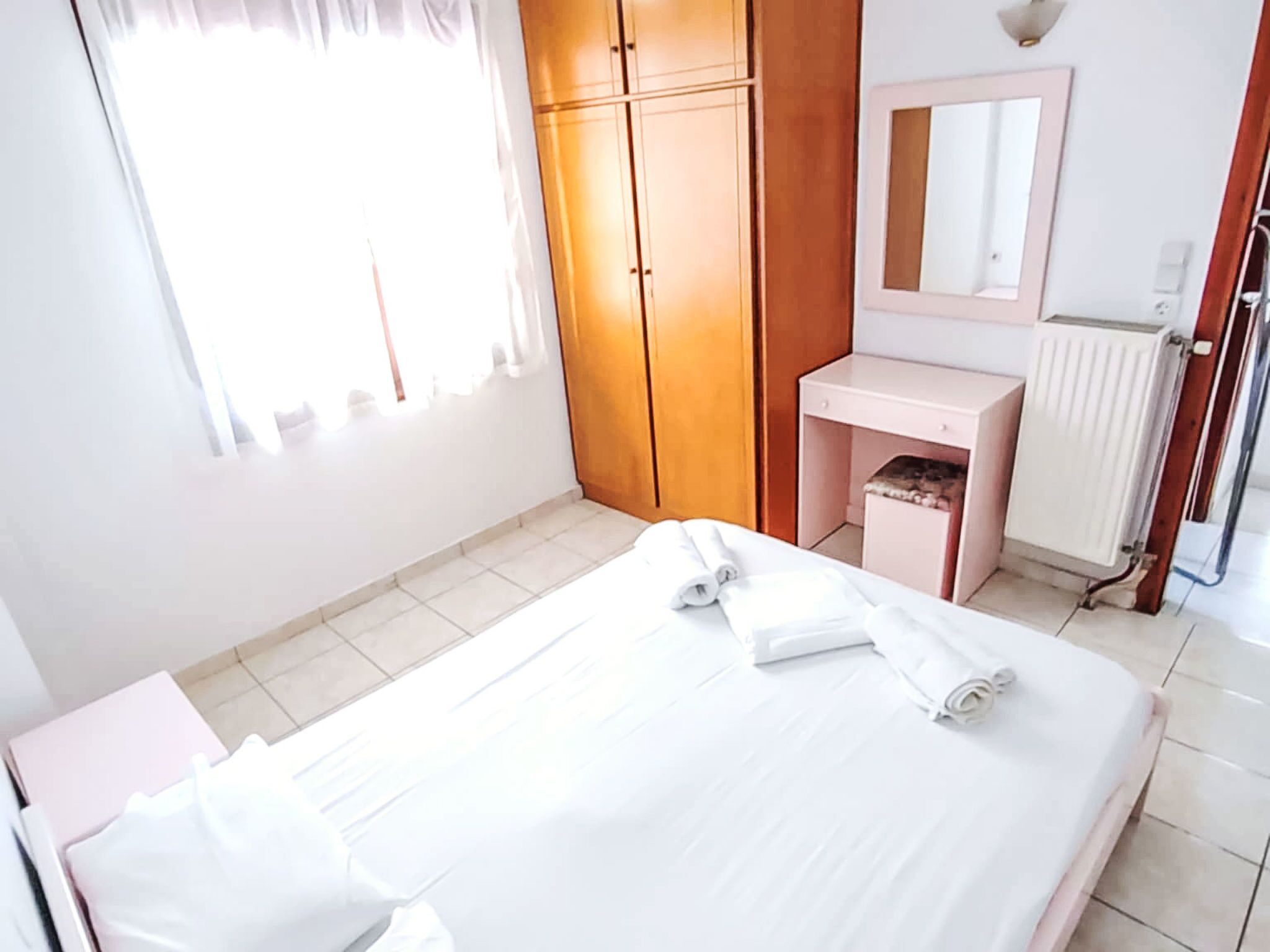 Een hotelkamer met een bed, een kaptafel met spiegel, een garderobe en een radiator.
