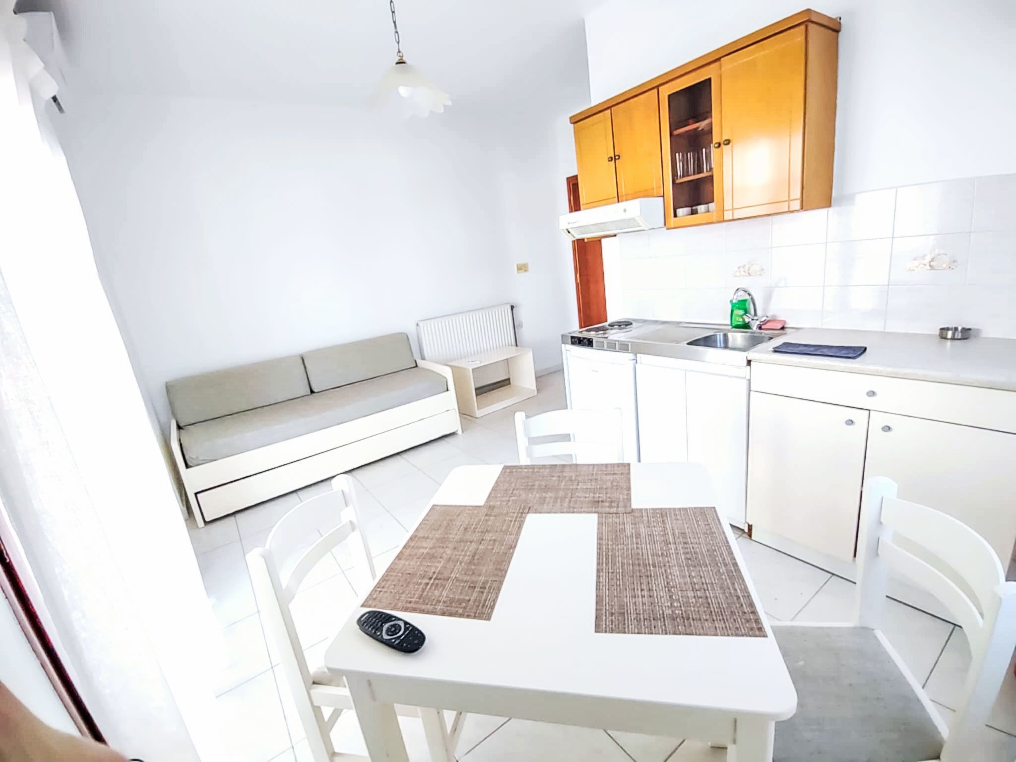 Een kleine keuken met witte kastjes, een eettafel en een inbouwbank.