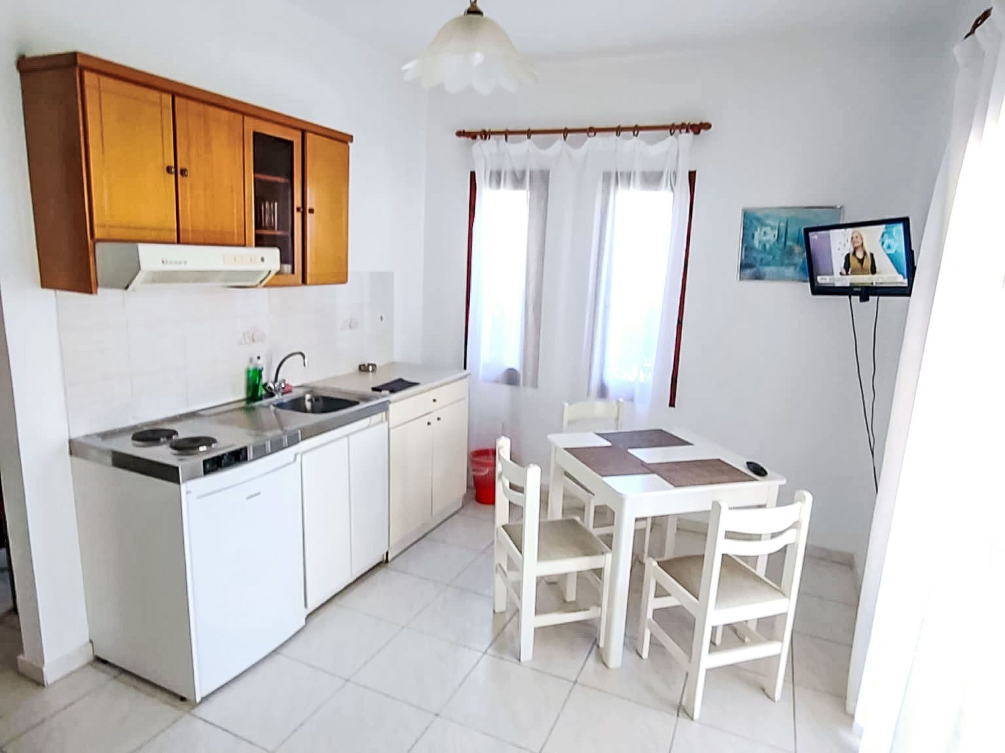 A compact kitchen with white cabinets, a stove, and a dining area with a table and chairs.