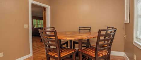 Un comedor con una mesa redonda de madera y cuatro sillas.