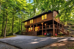 Eine zweistöckige Holzhütte mit einer Veranda und einer Treppe, die zu einer oberen Ebene führt.