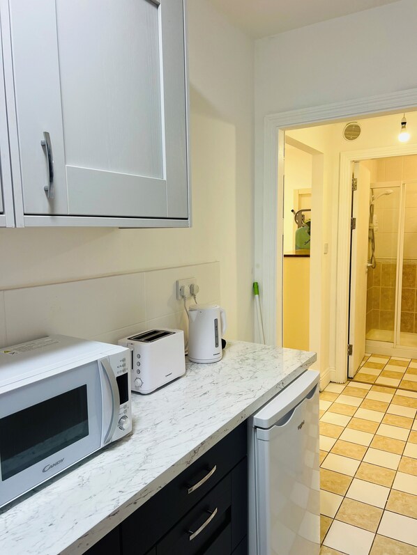 A kitchen with a microwave, toaster, and kettle on a marble countertop.