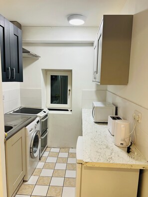 A compact kitchen with a washing machine, a microwave, and a toaster.