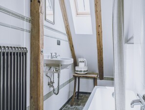 A bathroom with a white bathtub, a sink, and a small wooden stool. - Riverside Flat for Two Guests (Janowice Wielkie)