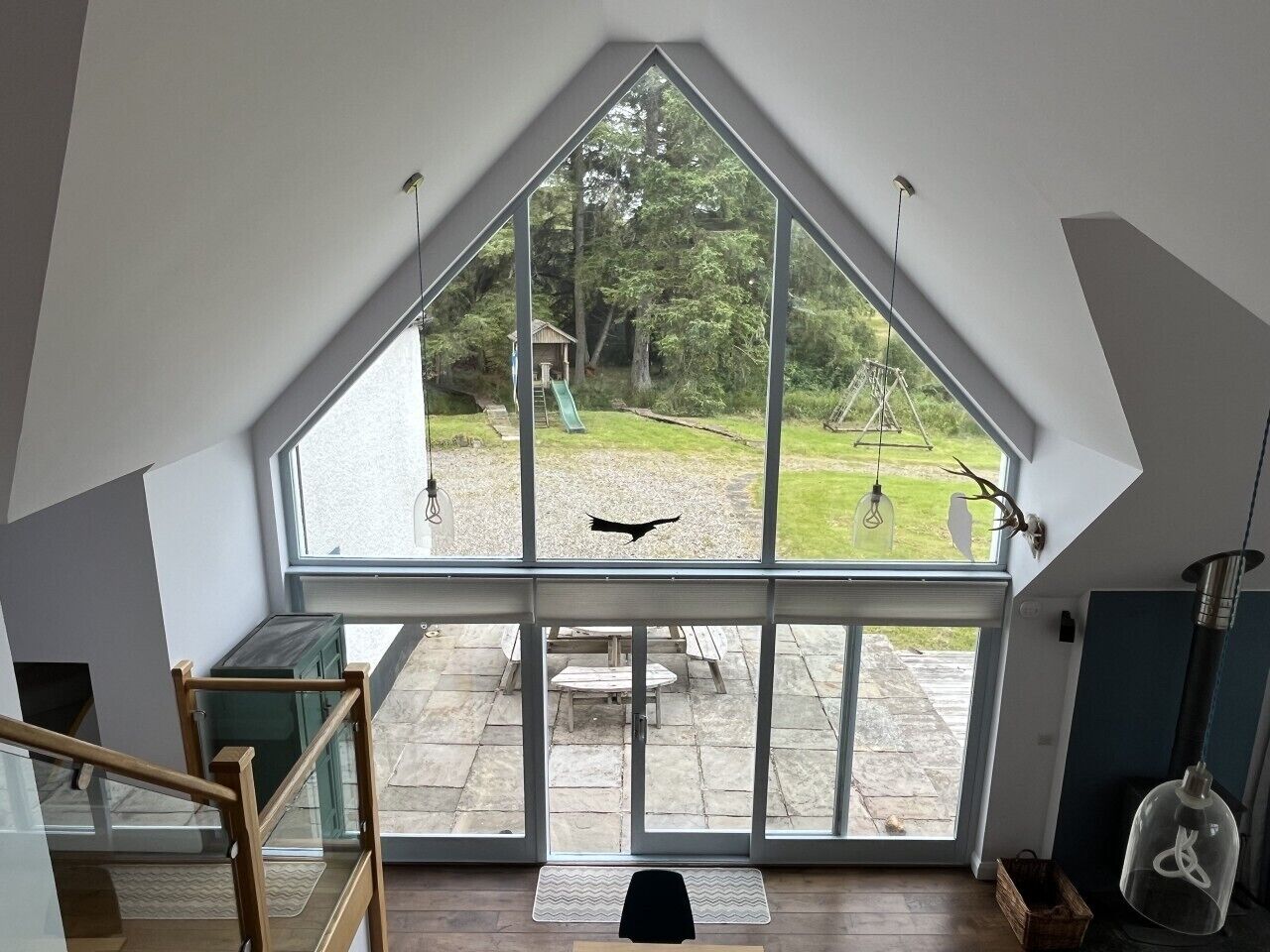 A room with a large window, a wooden bench, and a view of a garden.