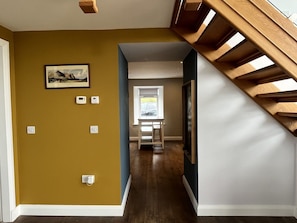 Ein Flur mit Treppe, einem Bilderrahmen an der Wand und einem Fenster am Ende.