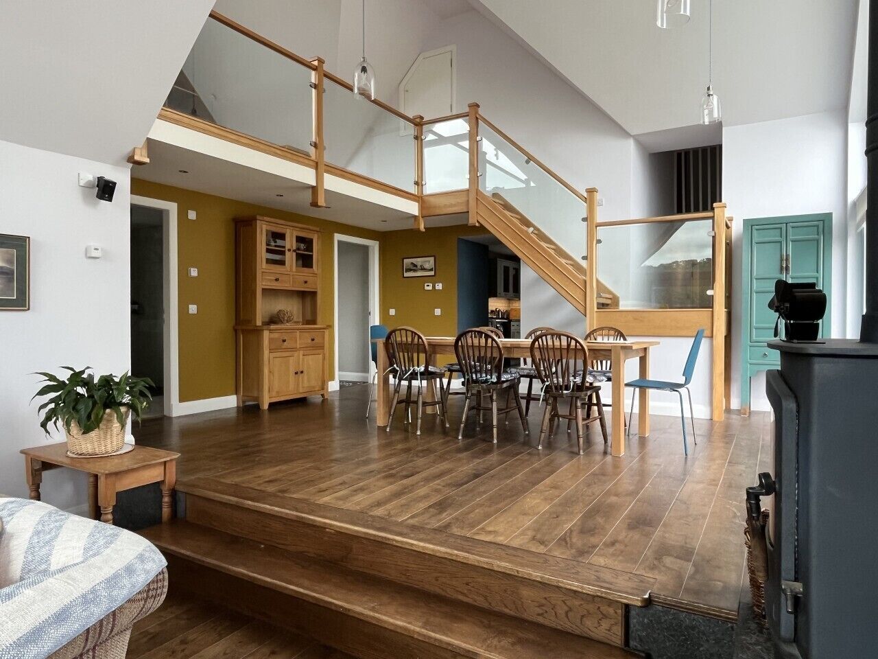Un vaste espace de vie comprenant un escalier en bois, une table à manger avec des chaises et un coin cuisine.