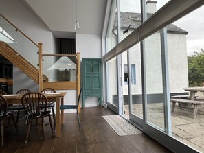 A modern interior with a dining area, staircase, and large sliding glass doors leading to an outdoor patio.