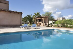 Ein Schwimmbecken mit zwei Liegestühlen und einer Pergola im Hintergrund.