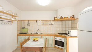 A compact kitchen with a wooden table, a sink, a stove, and a microwave. - Country Home “Servera” with Pool, Wi-Fi, Terrace & Garden (Santanyí)
