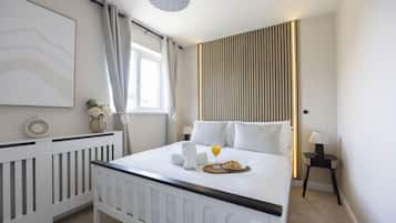 Ett hotellrum med en säng, ett sängbord, en lampa och ett fönster med gardiner.