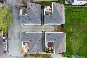A four-story building with a central courtyard, each floor featuring a distinct outdoor seating area. - 3 Luxury Homes • 12BR • 3 Rooftops • Sleeps 30 (Houston)