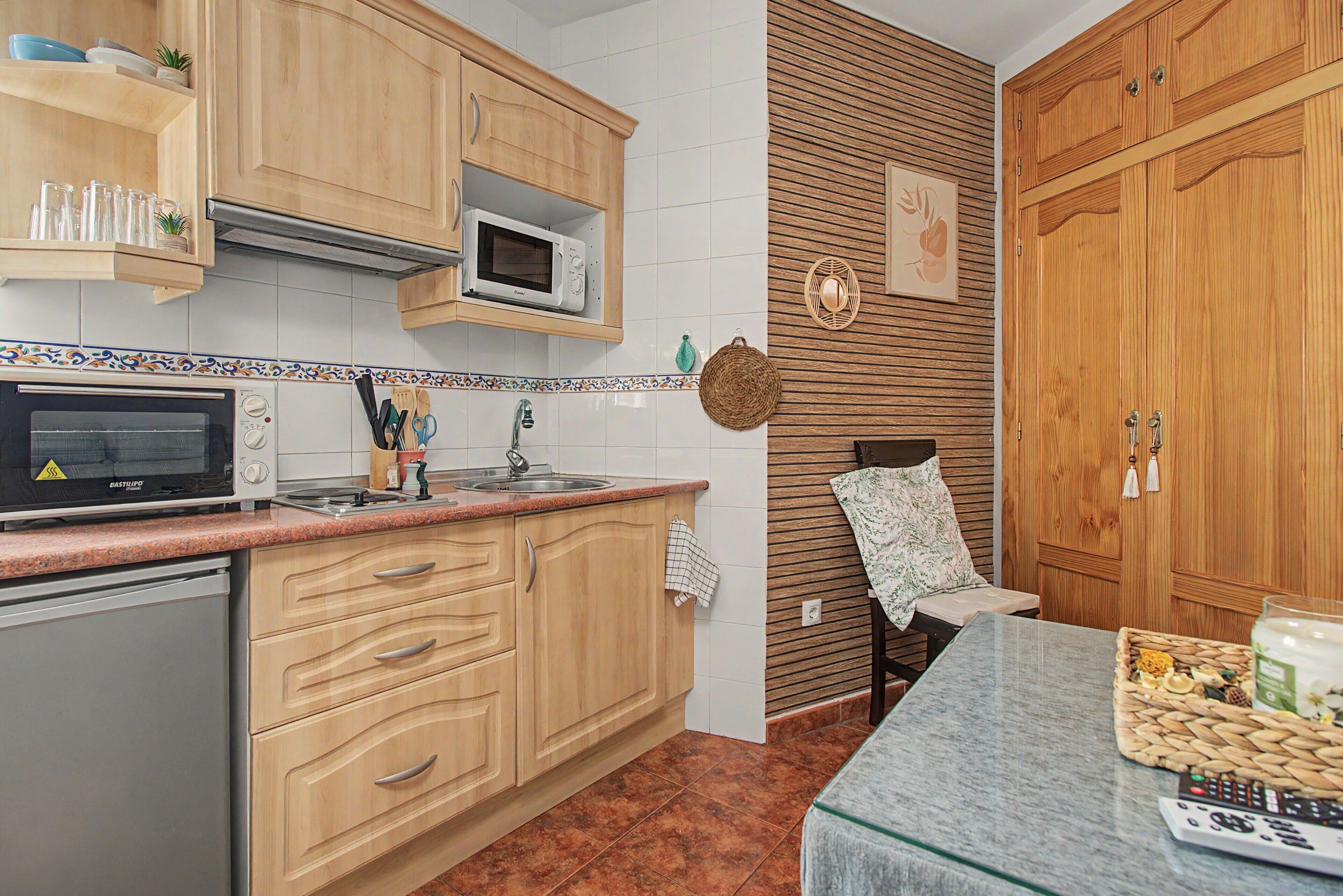 Una cocina con gabinetes de madera, microondas, pileta y estufa.