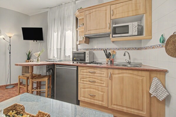 Una cucina compatta con mobili in legno, un forno a microonde, un tostapane e un lavandino.